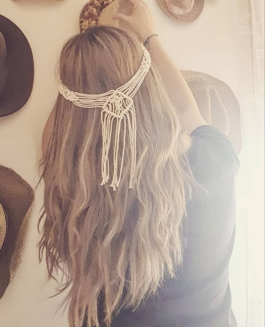 Olga d'esquena amb diadema de macramé i barrets penjats a la paret