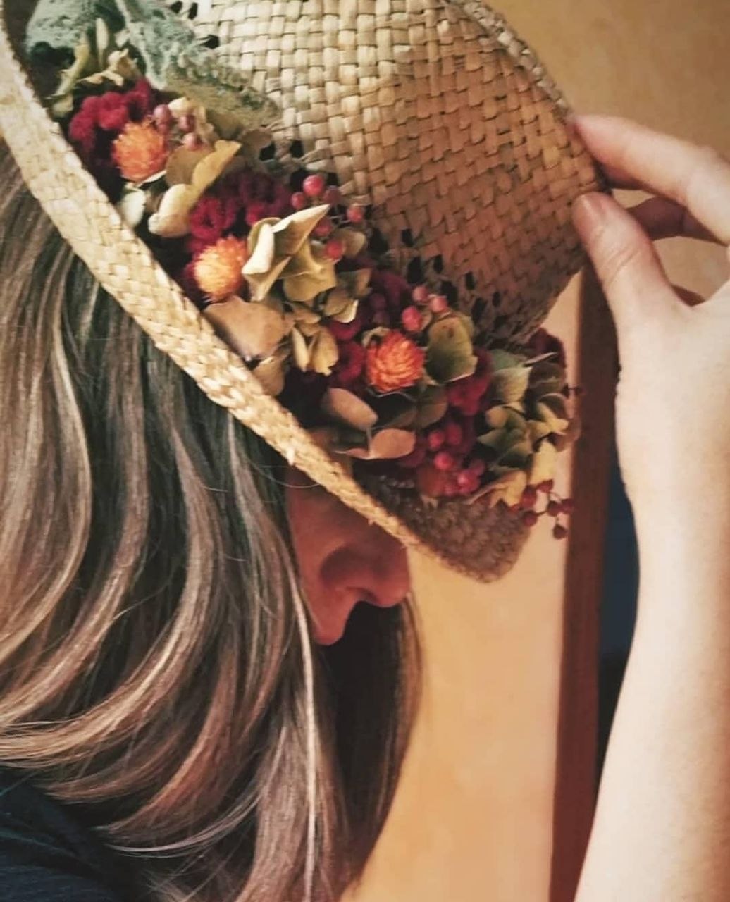 Olga portant un barret de palla decorat amb flors seques vermelles