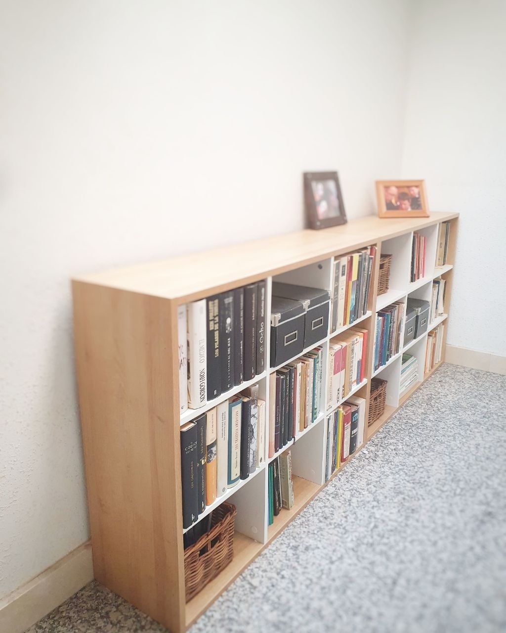 Prestatgeria de fusta amb llibres i cistelles